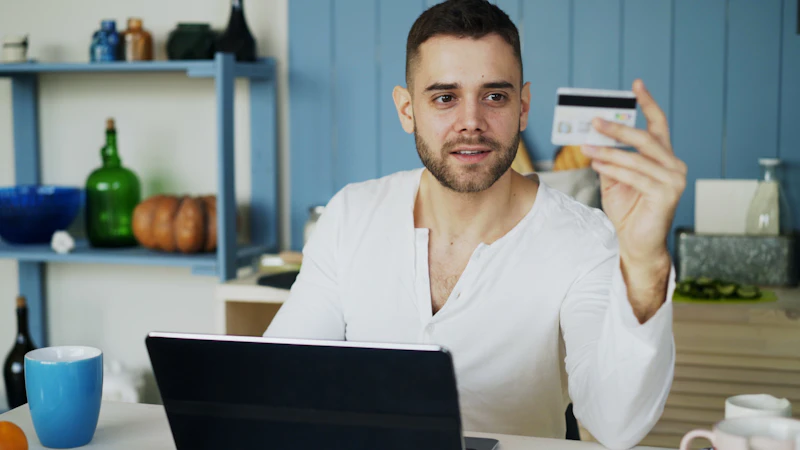 Ein Mann bezahlt beim Online-Einkauf mit Kreditkarte an einem Laptop.