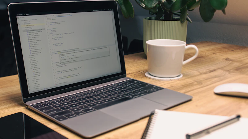 Laptop, Notizbuch und Smartphone liegen übersichtlich auf einem Schreibtisch.